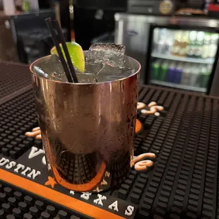 a cocktail in a copper cup with a lime wedge