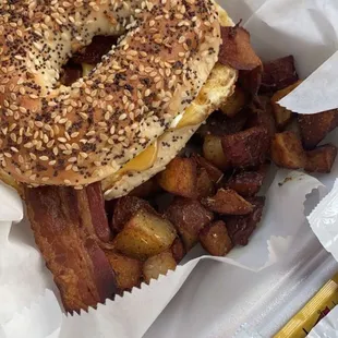 a bagel sandwich with bacon and potatoes