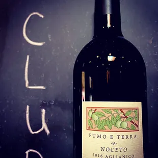 a bottle of wine with a chalkboard in the background