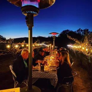 a group of people sitting at a dinner table with a patio heater