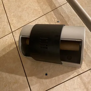 a toilet paper dispenser on a tiled floor