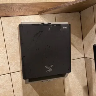 a black paper towel dispenser in a bathroom