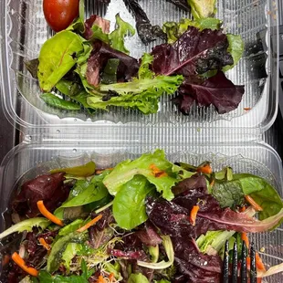 two plastic containers with salad and a fork
