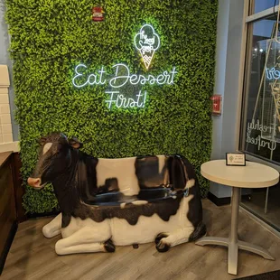 a cow statue in front of a green wall
