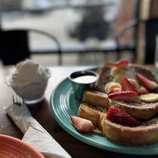 a plate of french toast with strawberries and bananas