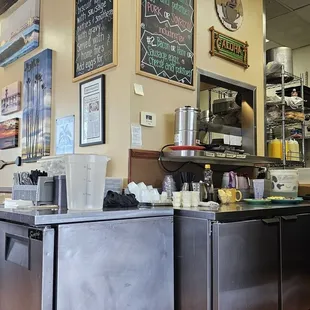 a restaurant counter with a menu on the wall