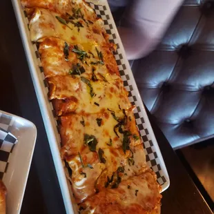 a long rectangular pizza with cheese and herbs