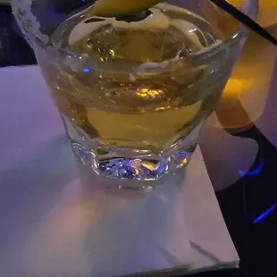 a glass of alcohol with a lemon wedge in it