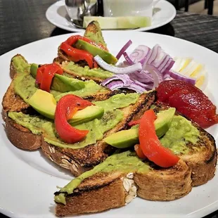 Avocado Toast - Multigrain wheat toast topped with chunky mashed avocado, roasted red pepper, Bermuda onion, hardboiled egg, and tomato jam