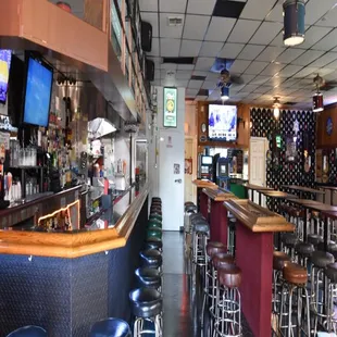 a bar with stools and televisions