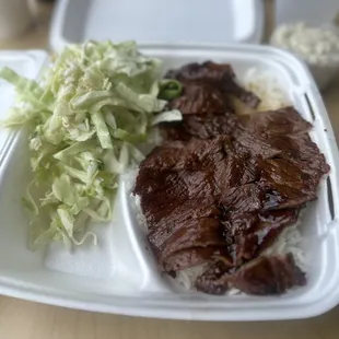 a plate of meat, rice, and coleslaw