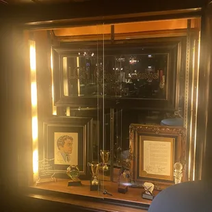 Vitrine with caricature drawings and trophies.