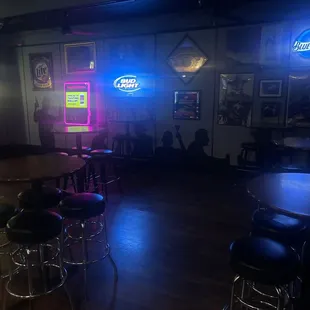 a bar with stools and neon signs