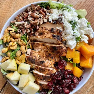 a bowl of chicken, rice, fruit, and nuts