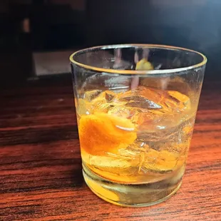 a glass of whiskey with orange peels