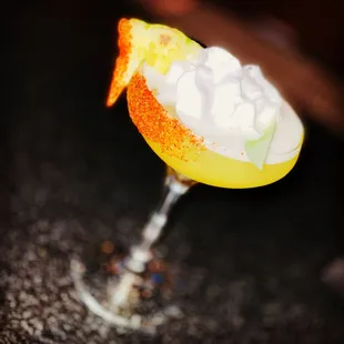a cocktail with whipped cream and orange peel