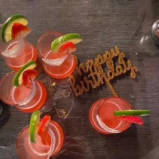 four glasses of cocktail with lime and strawberries