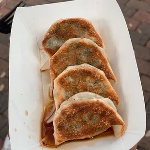 four dumplings in a paper container