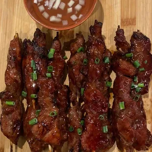 a plate of meat skewers with dipping sauce