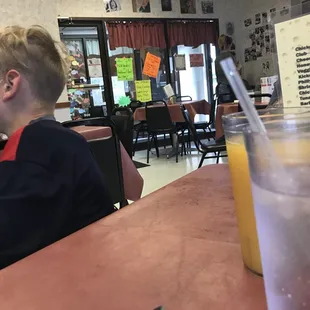 a boy sitting at a table with a glass of orange juice