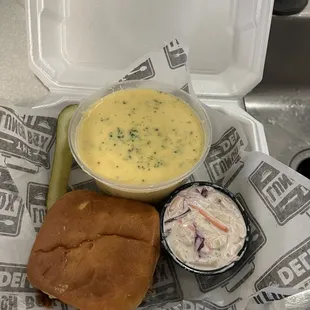 Pulled pork sandwich, bowl of broccoli cheese soup, and side of coleslaw
