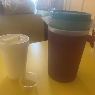 a plastic cup and a plastic jug on a yellow table