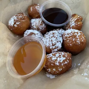powdered sugared doughnuts and a cup of syrup