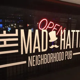 a neon sign for the mad hatter neighborhood pub