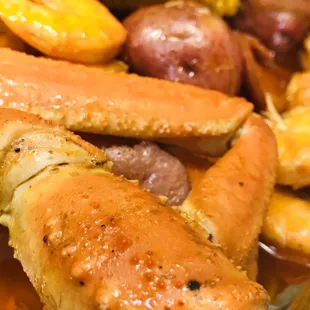 a plate of cooked crab legs, potatoes, and corn