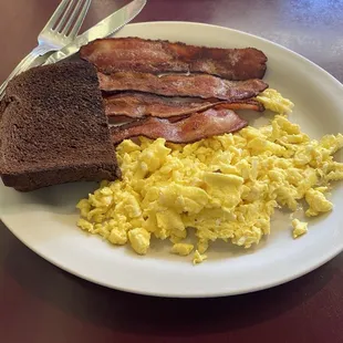 Two scrambled eggs, bacon and rye toast