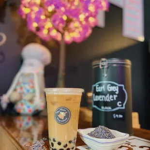 a cup of bubble tea and a canister of lavender sprinkles