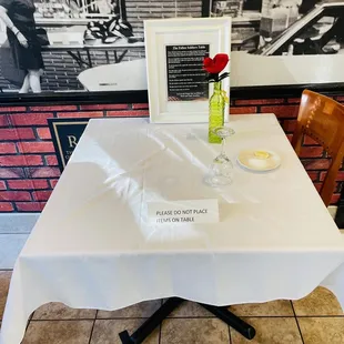 a table with a white tablecloth and a red rose