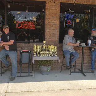 three men sitting at a table outside a restaurant