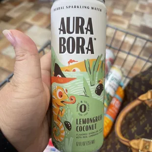 a person holding a can of aura bora
