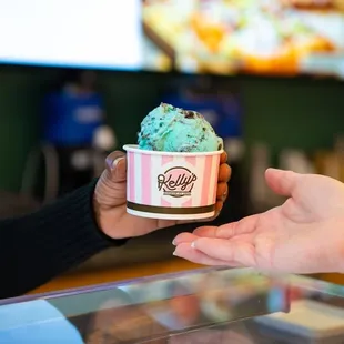 A cup of Kelly's Homemade Ice Cream being handed over to the guest.