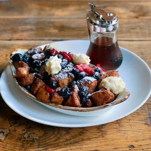 a plate of french toast with berries and cream