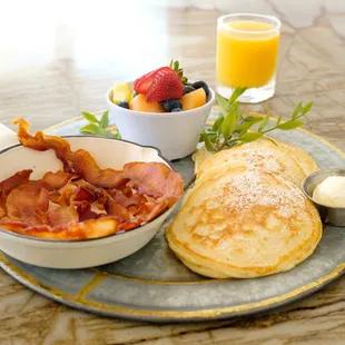 Buttermilk pancakes served with bacon, fresh fruit, and fresh squeezed orange juice.