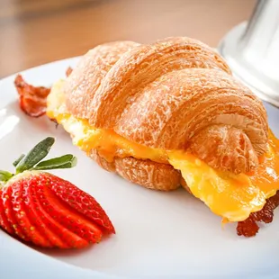 a croissant sandwich and a strawberry