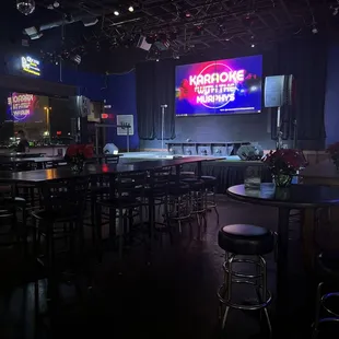 a bar with bar stools and neon signs