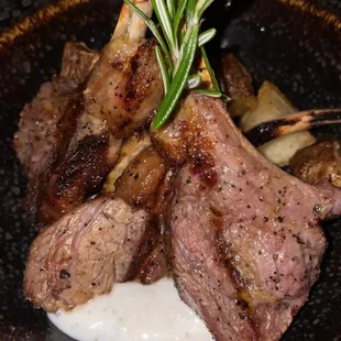 a plate of lamb chops with a sprig of rosemary