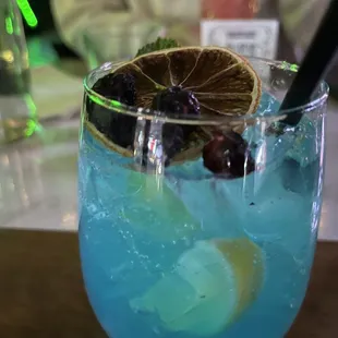a blue drink with a slice of lemon