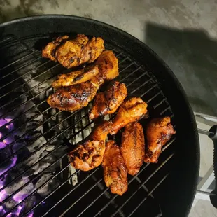 a charcoal grill with chicken wings on it