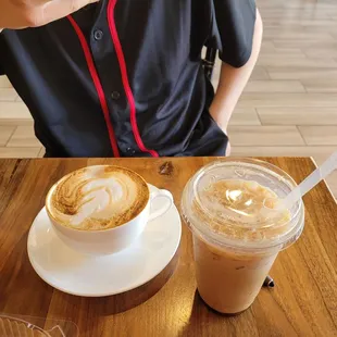 a woman sitting at a table with two cups of coffee