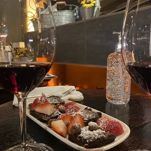 a plate of chocolate covered strawberries and a glass of red wine