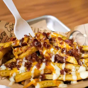 a plate of french fries with cheese and bacon