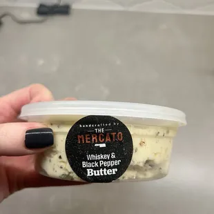 a hand holding a tub of butter