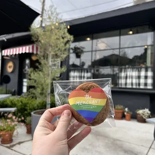 a person holding a cookie in front of a building