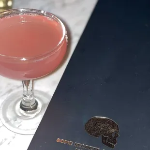 a pink cocktail in a coupe glass