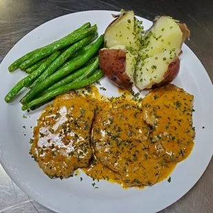 a plate of meat, potatoes, and green beans