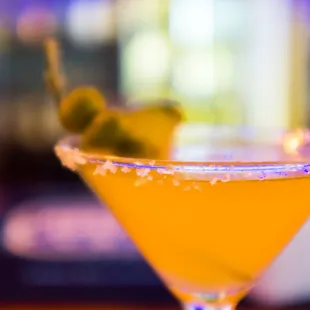 a martini with a green olive garnish